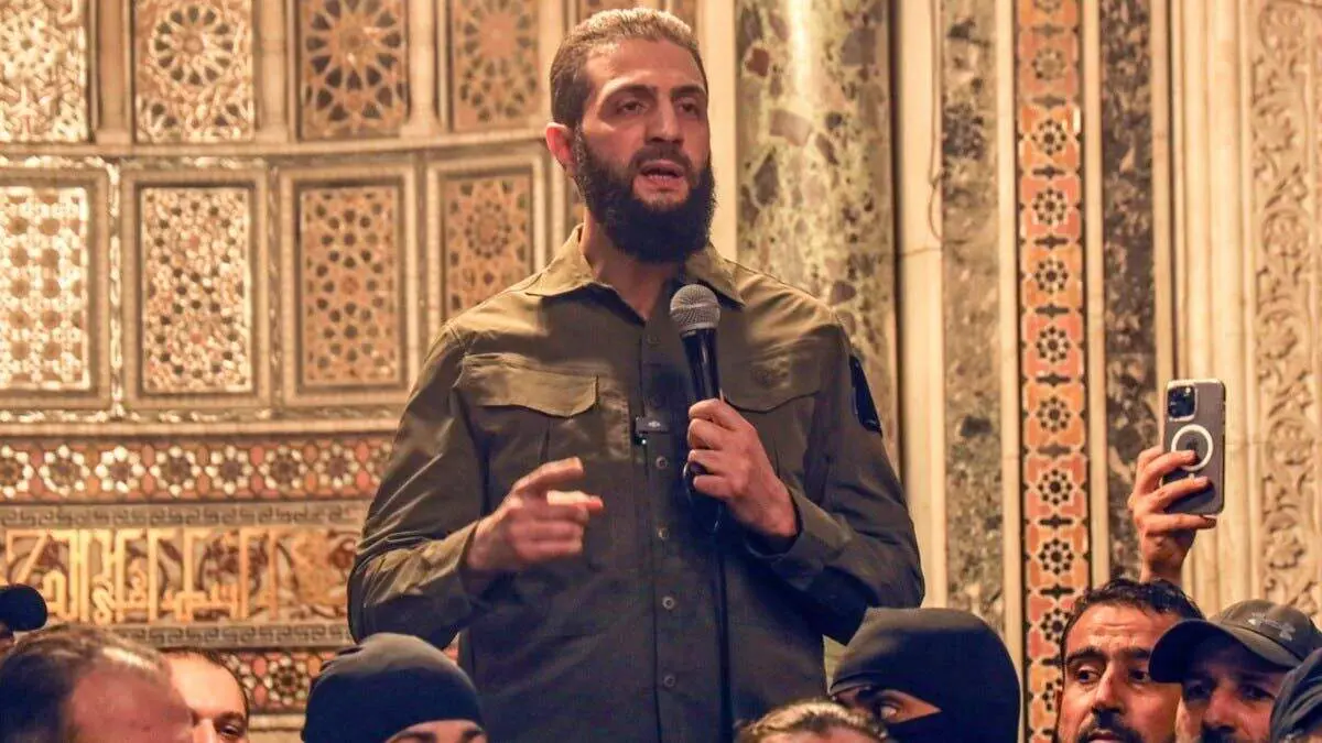 محمد الجولانی زیر کت و شلوارش سلاح پنهان می‌کند + ببینید 