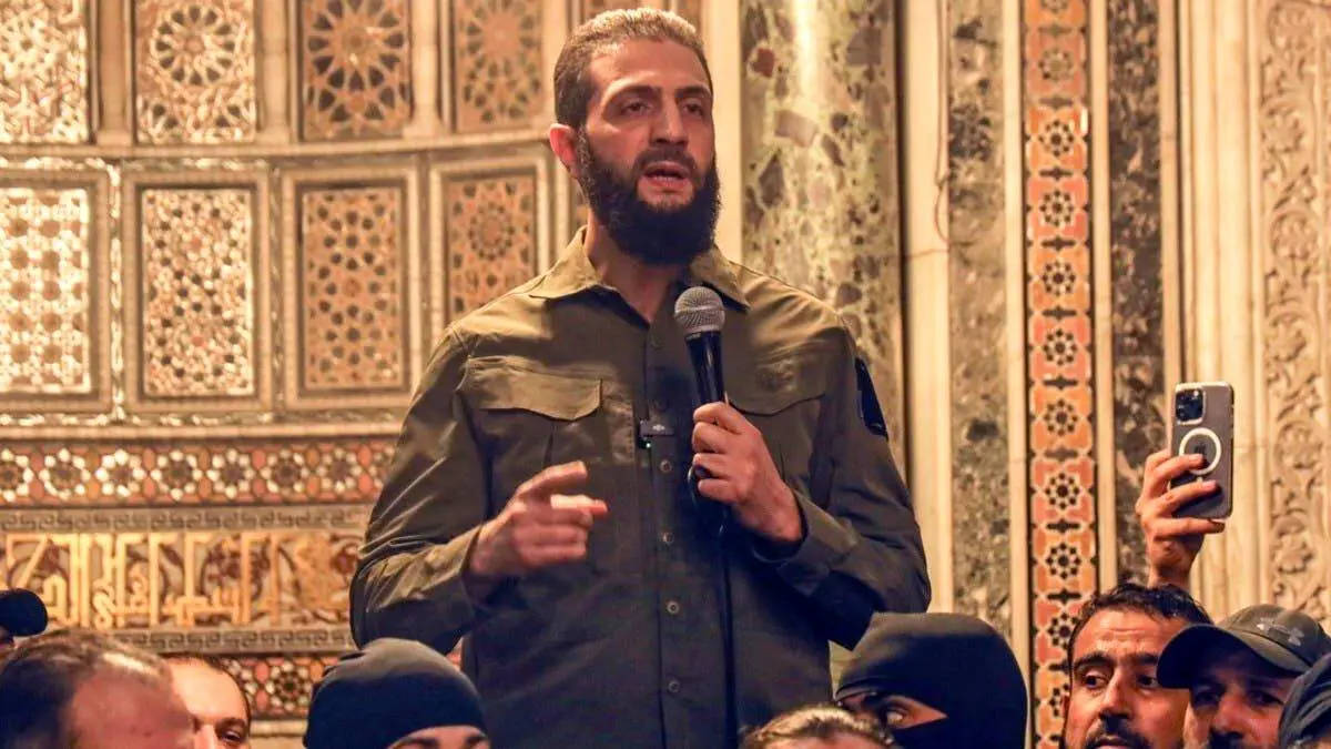 محمد الجولانی زیر کت و شلوارش سلاح پنهان می‌کند + ببینید 